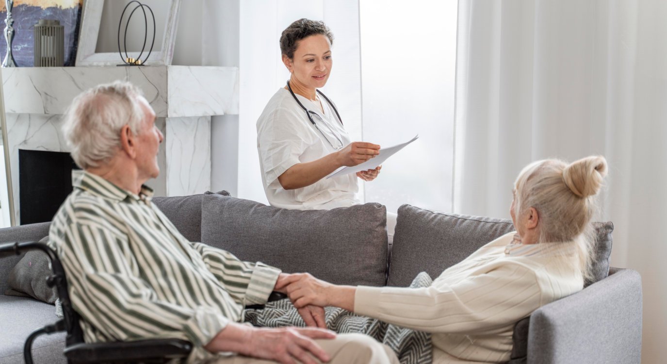 Caretakers with senior couple sitting in living room at nursing home