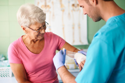 a caregiver bandaging an elderly hand