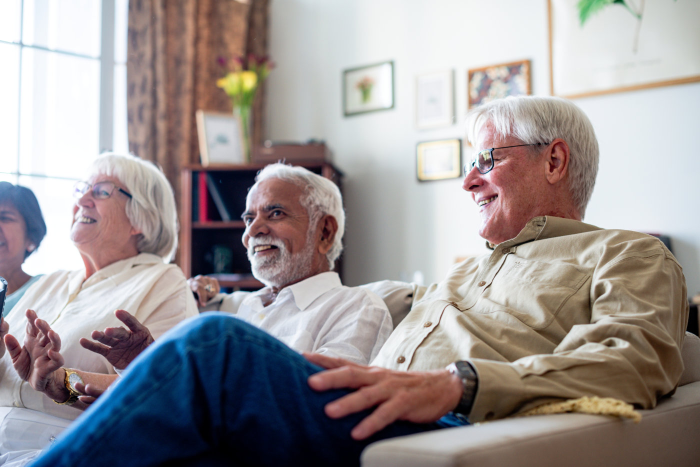 Group of elderly friends laughing and enjoying time together indoors.