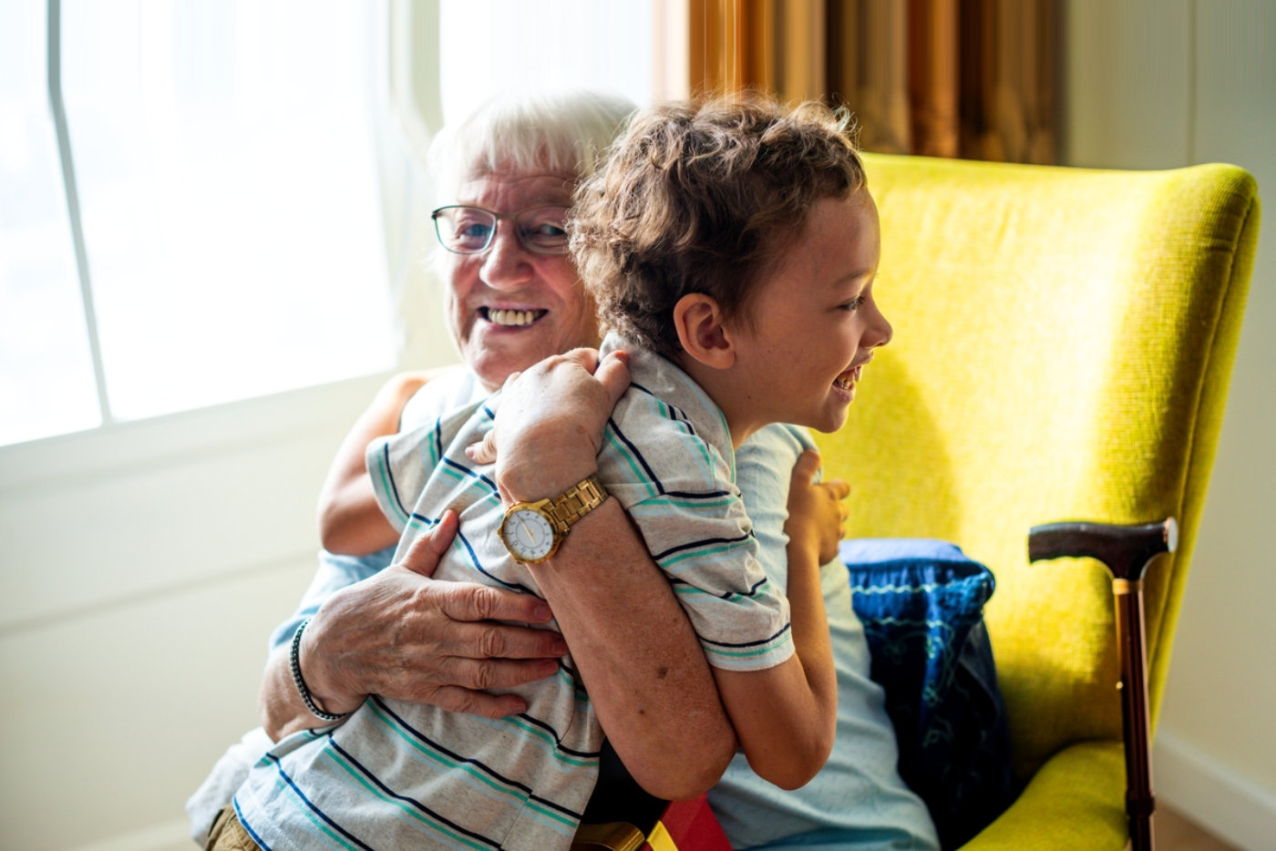 Elderly woman and young boy hugging in a cozy room.
