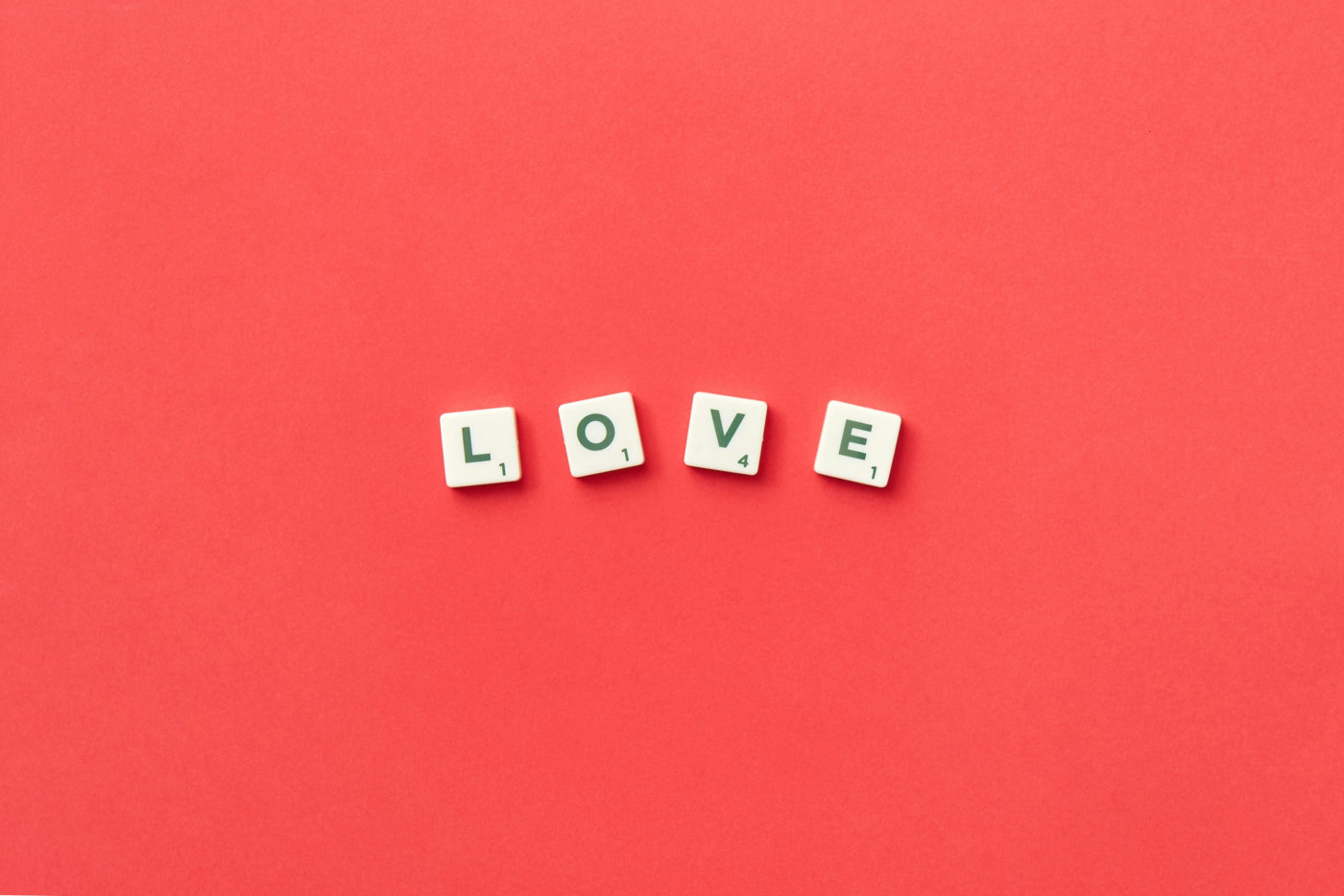 Scrabble letters spelling "love" on a vibrant red background.